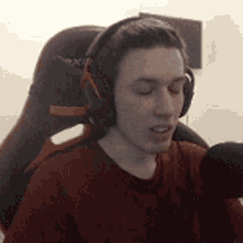 a young man wearing headphones and a red shirt is sitting in a chair .