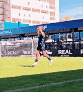 a soccer player runs on a field with a sign that says real on it