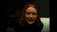 a woman with long red hair is standing in a dark room and laughing .