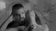 a black and white photo of a man and a woman kissing .