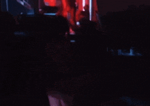 a group of people are standing in a dark room with red lights behind them