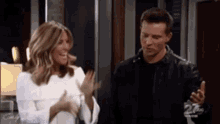 a man and a woman are standing next to each other in a living room and laughing .