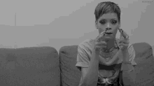 a black and white photo of a woman sitting on a couch with her fingers crossed .