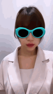 a woman wearing blue sunglasses and a white coat