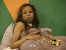 a woman is laying on a bed with a blanket on her stomach and says ha !