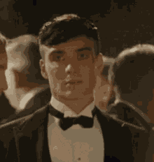 a man in a tuxedo and bow tie is looking at the camera .