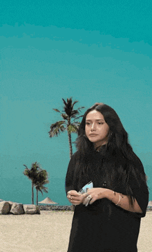 a woman in a black shirt is standing on a beach