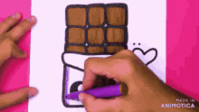 a person is drawing a chocolate bar with a heart on it with a purple marker