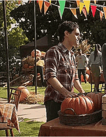 a man in a plaid shirt is standing next to a table with pumpkins .