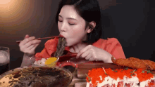 a woman is eating noodles with chopsticks at a table
