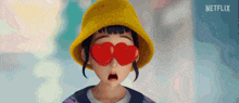 a cartoon girl wearing a yellow hat and heart shaped glasses .