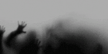 a blurry picture of a person 's hands reaching out from behind a foggy glass .