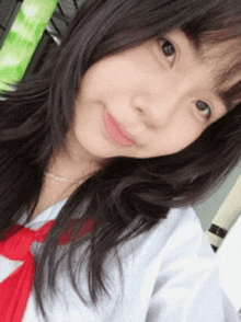 a girl wearing a white shirt and a red tie looks at the camera