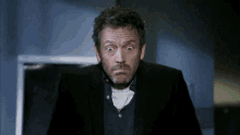 a man in a suit and a blue shirt is making a funny face .