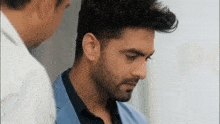 a man with a beard is standing next to another man in a blue suit .