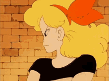 a cartoon girl with blonde hair and a red bow in her hair stands in front of a brick wall .