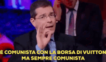 a man in a suit and tie says " e comunista con la borsa di vuitton ma sempre comunista " .