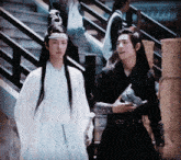 a man in a white robe and a man in a black robe are walking down stairs