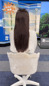 a woman with long hair is sitting in a chair in front of a wnn sign