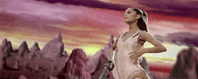 a woman in a white dress is standing in front of a mountain holding a guitar .