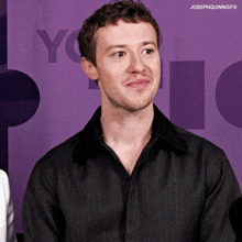 a man in a black shirt is smiling in front of a purple background that says " you "