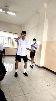 a boy wearing a mask stands in a classroom