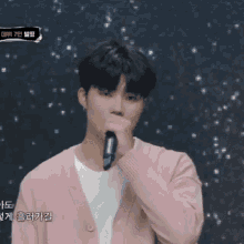 a man in a pink cardigan is holding a microphone