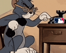 a cartoon of tom talking on a phone with a mlb logo on the table behind him