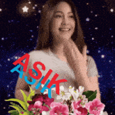 a woman holding a bouquet of pink and white flowers with the word asik written in red