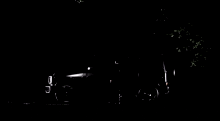 a man is sitting in the driver 's seat of a black car in the dark .