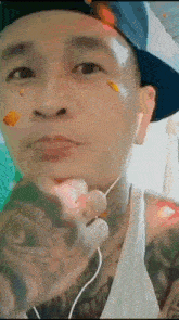 a man with a tattoo on his face is wearing a hat and ear buds .
