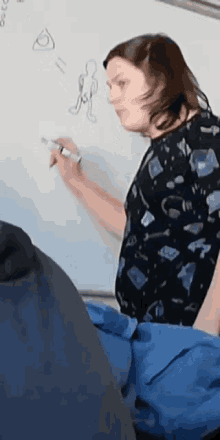 a woman drawing on a white board with a marker