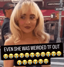 a woman with blonde hair is holding a sign that says " even she was weirded tf out " on it