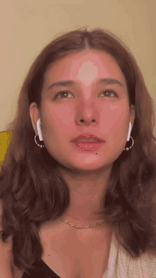 a close up of a woman 's face with earrings and a necklace