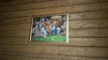 a framed painting of dogs playing pool on a wooden wall