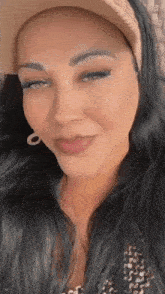 a close up of a woman wearing a hat and earrings .