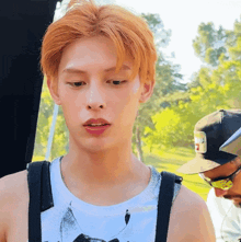a man with red hair is wearing a white tank top with the word tommy on it