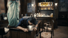 a man is laying on a desk with a woman behind him