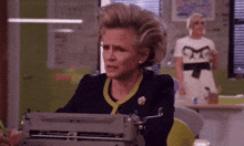 a woman is typing on a typewriter with a pencil in her hand .