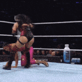 two women are wrestling in a ring with a bottle of prime water in the corner