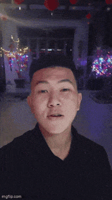 a man in a black shirt is standing in front of a room with lanterns on the ceiling ..