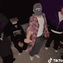 a group of people are dancing in a room with a tiktok logo on the bottom right