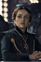 a woman wearing a green dress and a gold necklace with a star on it