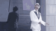 a man in a white suit and black tie is dancing in front of a building .