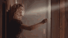 a woman is standing in front of a window in a dark room holding a flashlight .