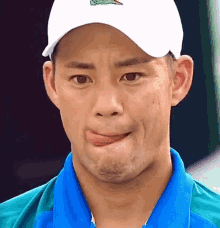 a man wearing a white hat and a blue shirt is making a face .