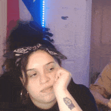 a woman with a tattoo on her wrist looks tired