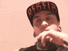 a man wearing a hat that says rebel is pointing at the camera .