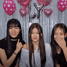three girls are posing for a picture in front of balloons and a curtain that says ly