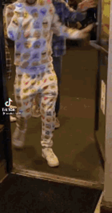 a man in a pajama suit is standing in a doorway .